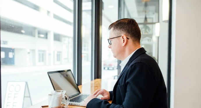 man using MacBook facing wall